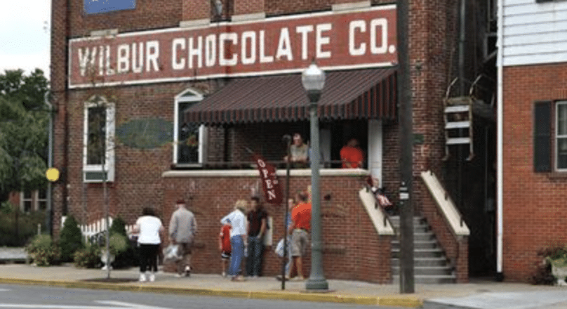 Brick building with an awning and people lined up outside of Wilbur Chocolate Co.